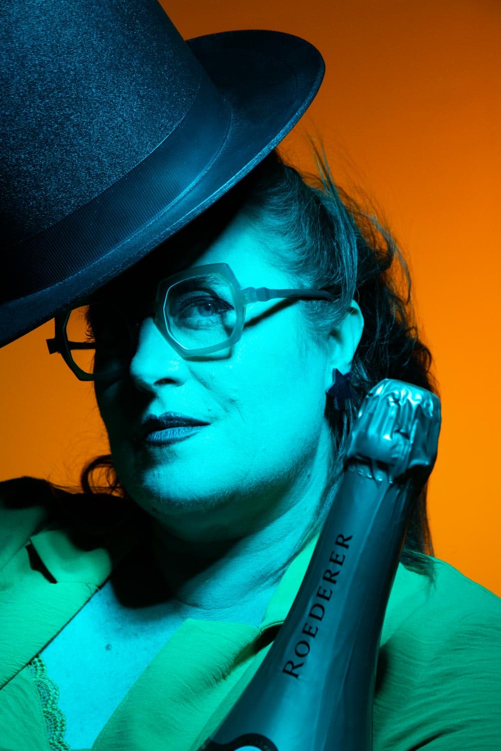 Lunettes signature, chapeau et bouteille de champagne sous une lumière théâtrale — offre Festival Volcanique